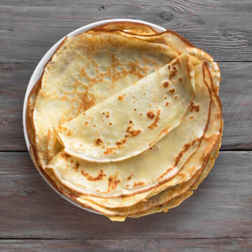 Thin crepe-style pancakes, pan-fried until golden and served warm in a stack.