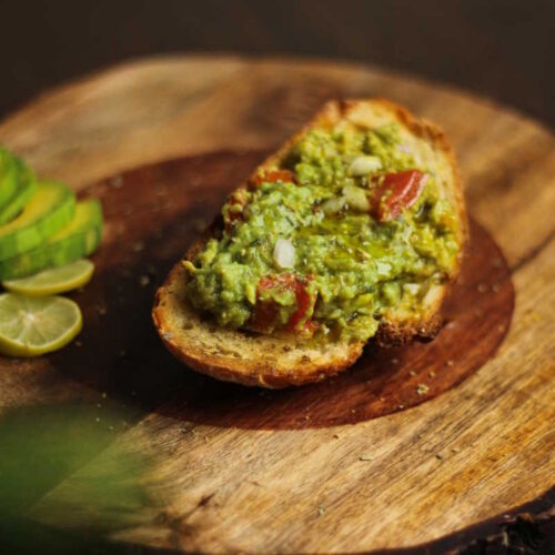 Smashed avocado with diced onion and tomato on sourdough toast.