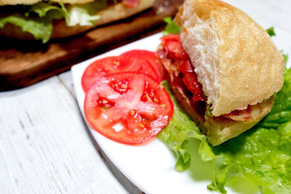 Vegan BLT sandwich, served on a plate with a fresh salad.